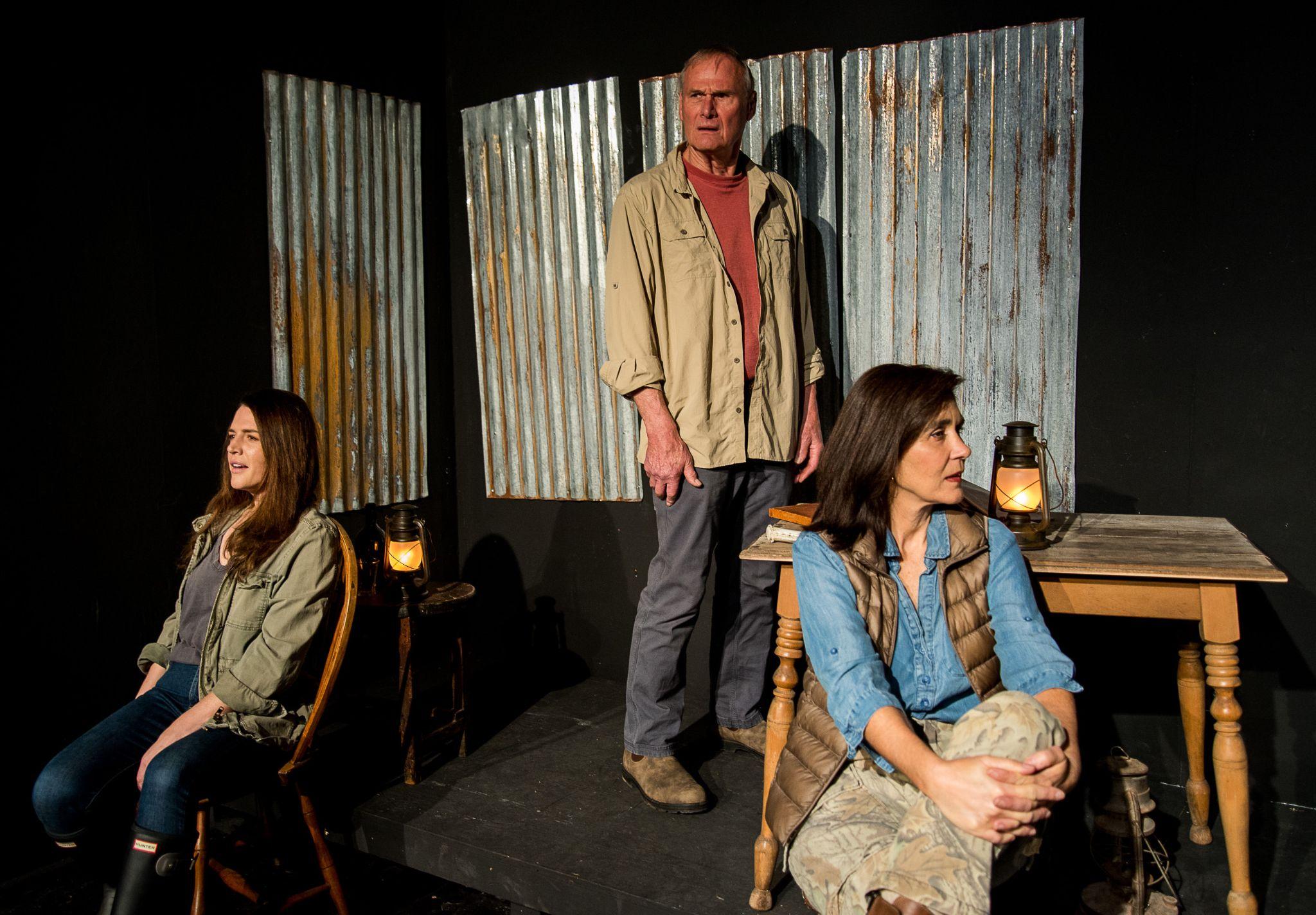 Press Photo from Haunting Play, THE RIVER at Live Arts: three people on stage with tables and lanterns