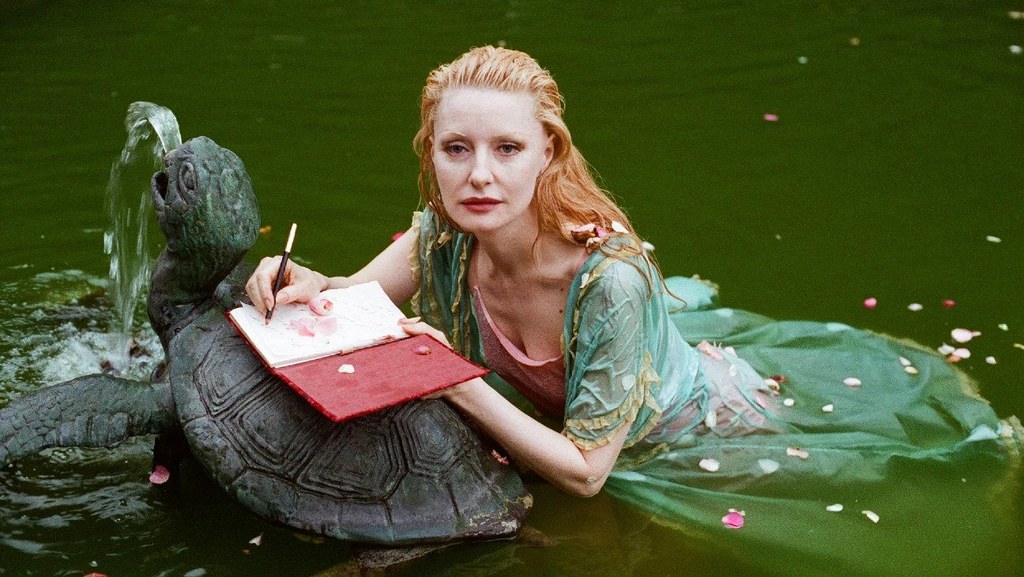Movie Still from THE DISAPPEARANCE OF SHERE HITE - a woman in the water writing in a journal
