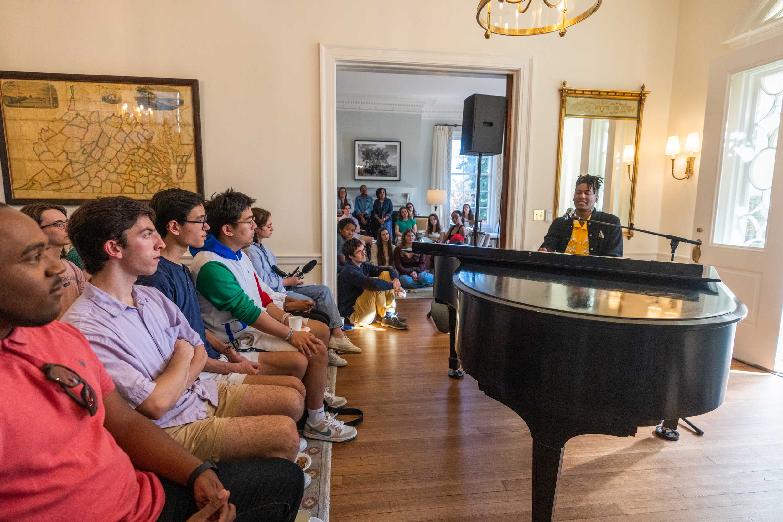 Audience members look on as musician Jon Batiste sings and plays the piano at Carr's Hill