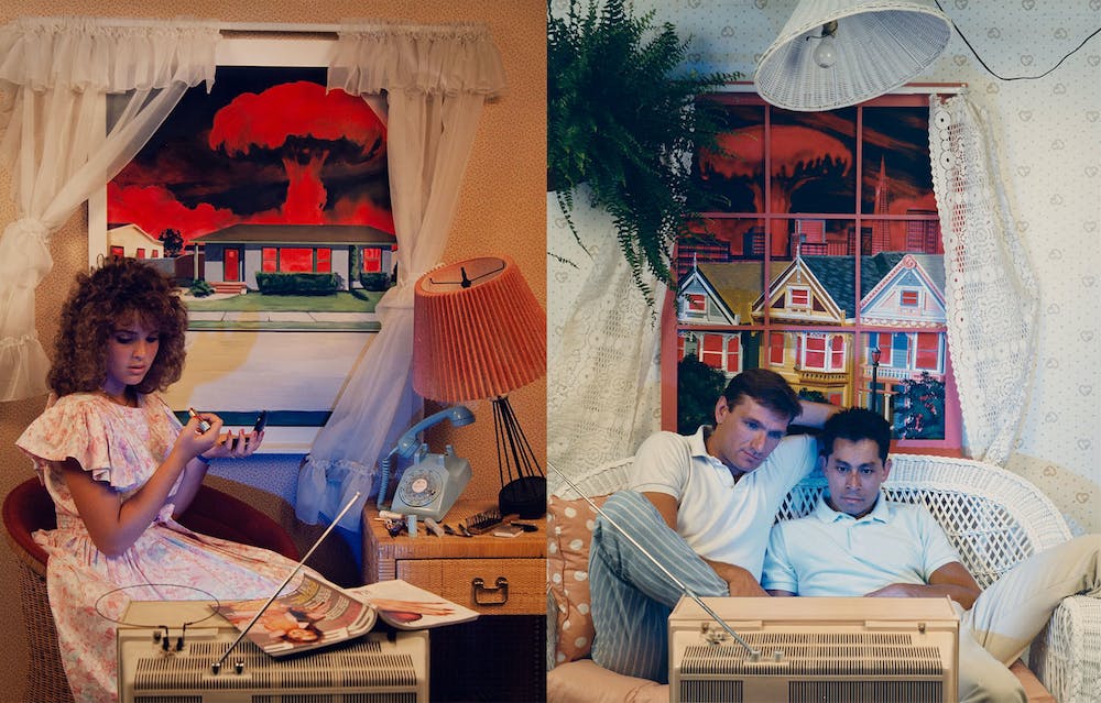Two photos from the "Radioactive Inactives" series by Patrick Nagatani and Andrée Tracey. The left shows a woman putting on makeup and watching TV while a red mushroom cloud can be seen through a window behind her; the right photo features two men watching TV on a couch, also with a red mushroom cloud in the background.