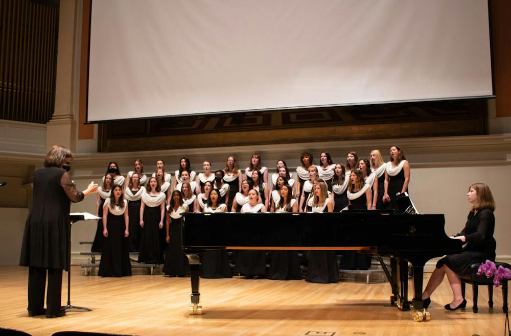 The Virginia Women's Chorus assembles on the stage of Old Cabell Hall, accompanied by a pianist. 