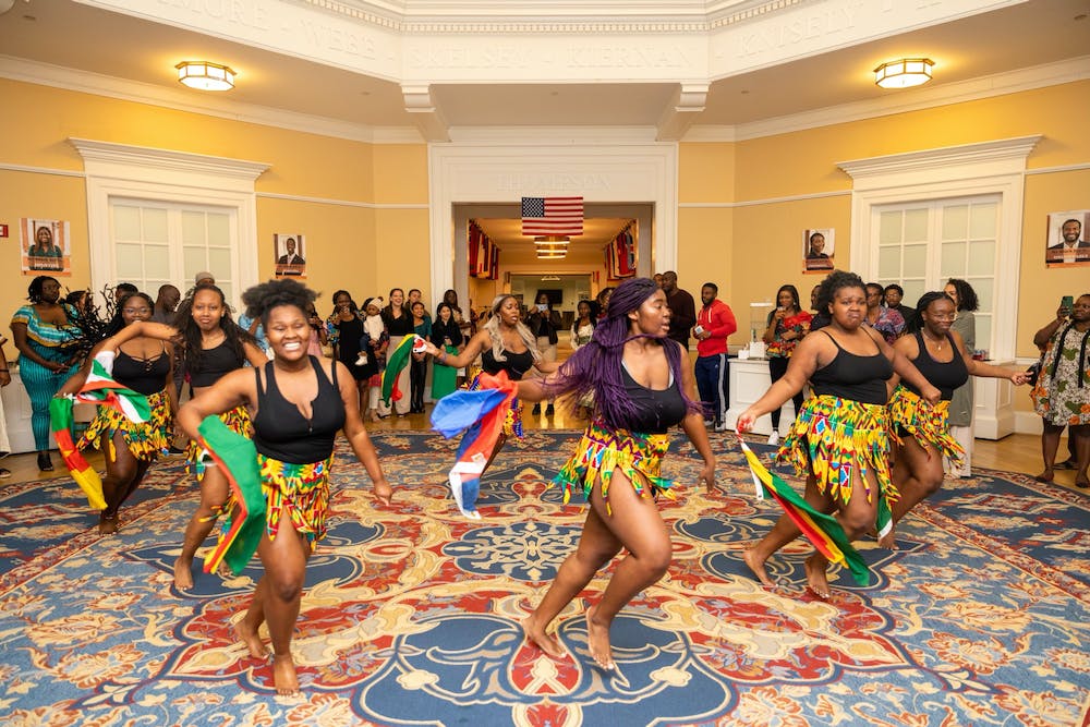 Afro-Hoos, a group of Black women dancers, perform a dance while smiling and holding flags.