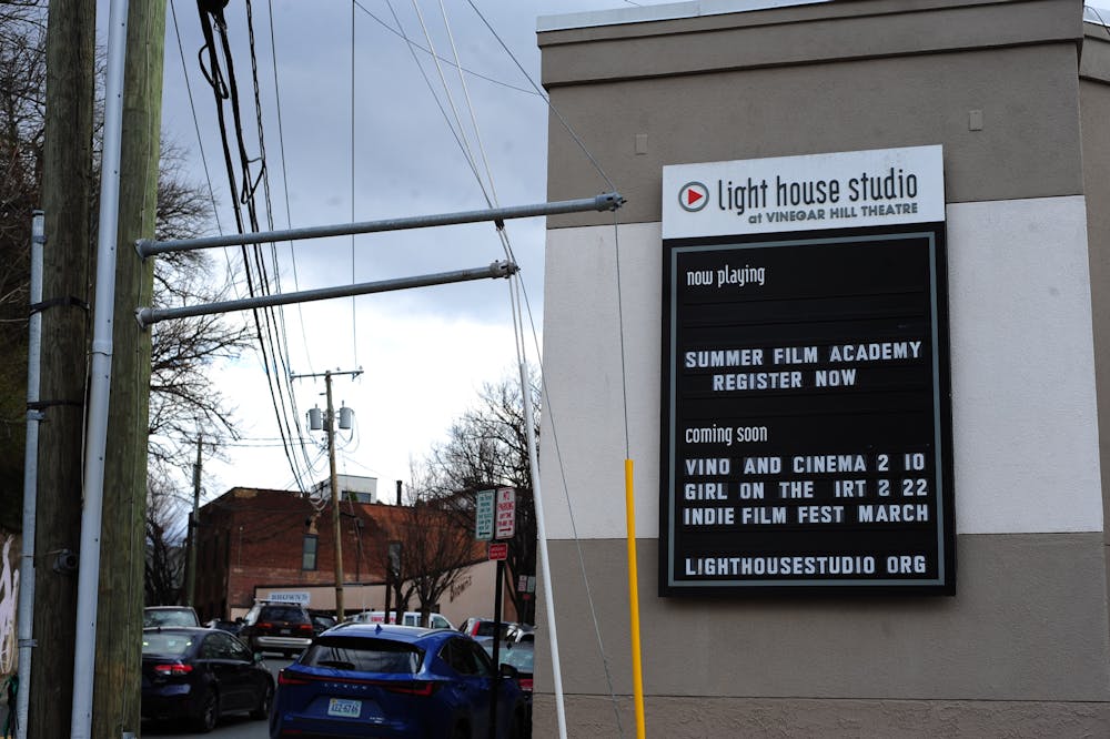 A photo of the outside of Lighthouse Studio, a beige building with a black sign that reads: "summer film academy register now" and "coming soon: vino and cinema 2/10, girl on the IRT 2/22, indie film fest march".  