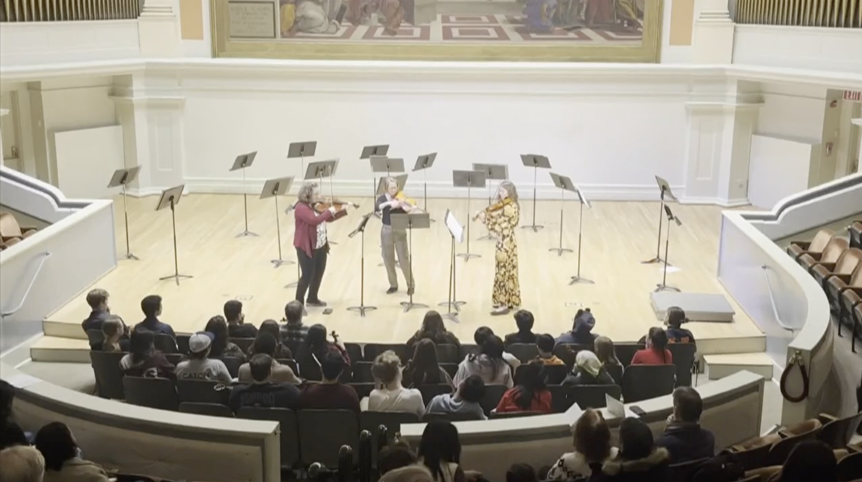 3 violists stand on the stage in Old Cabell Hall and play the viola to an audience.