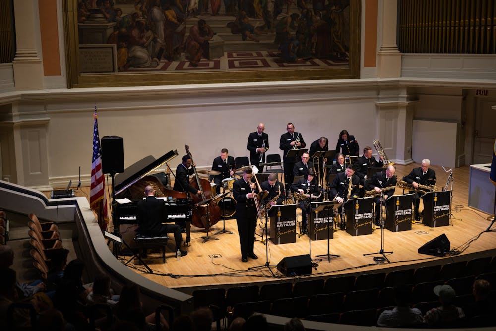The Commodores — featuring sixteen musicians in Navy uniform, some on brass, others on keys or strings — perform onstage in Old Cabell Hall.