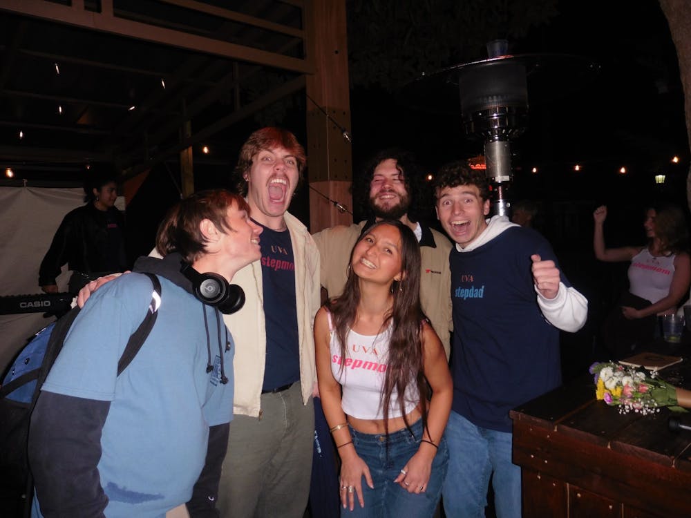 Five student stand-up comics smile for a photo at an outdoor bar. 