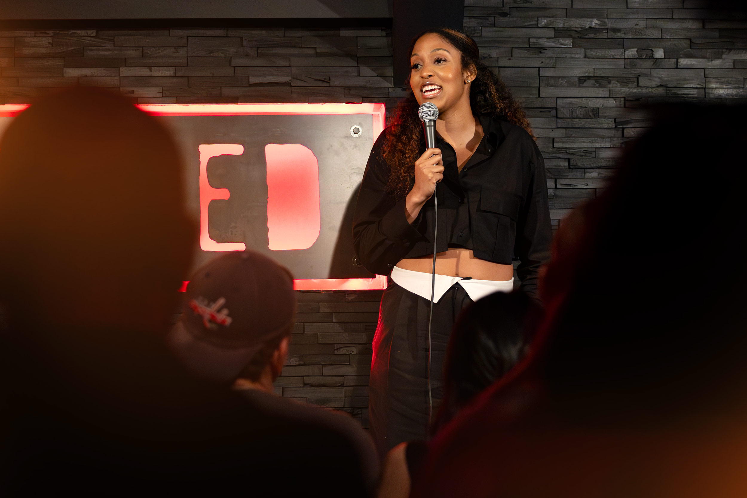 Jasmine Burton holds a microphone and smiles onstage.