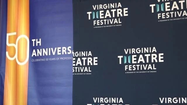 A photo of a backdrop for the Virginia Theatre Festival that reads both "Virginia Theatre Festival" and "50th Anniversary."