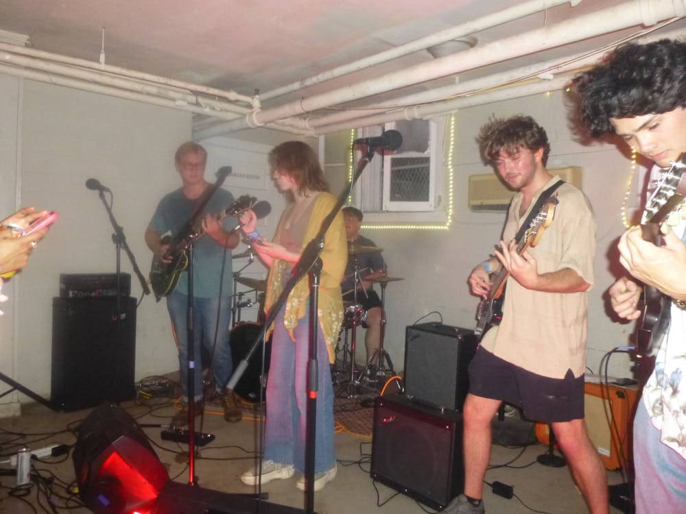 Five students play instruments in a basement, covered in a hazy glow.