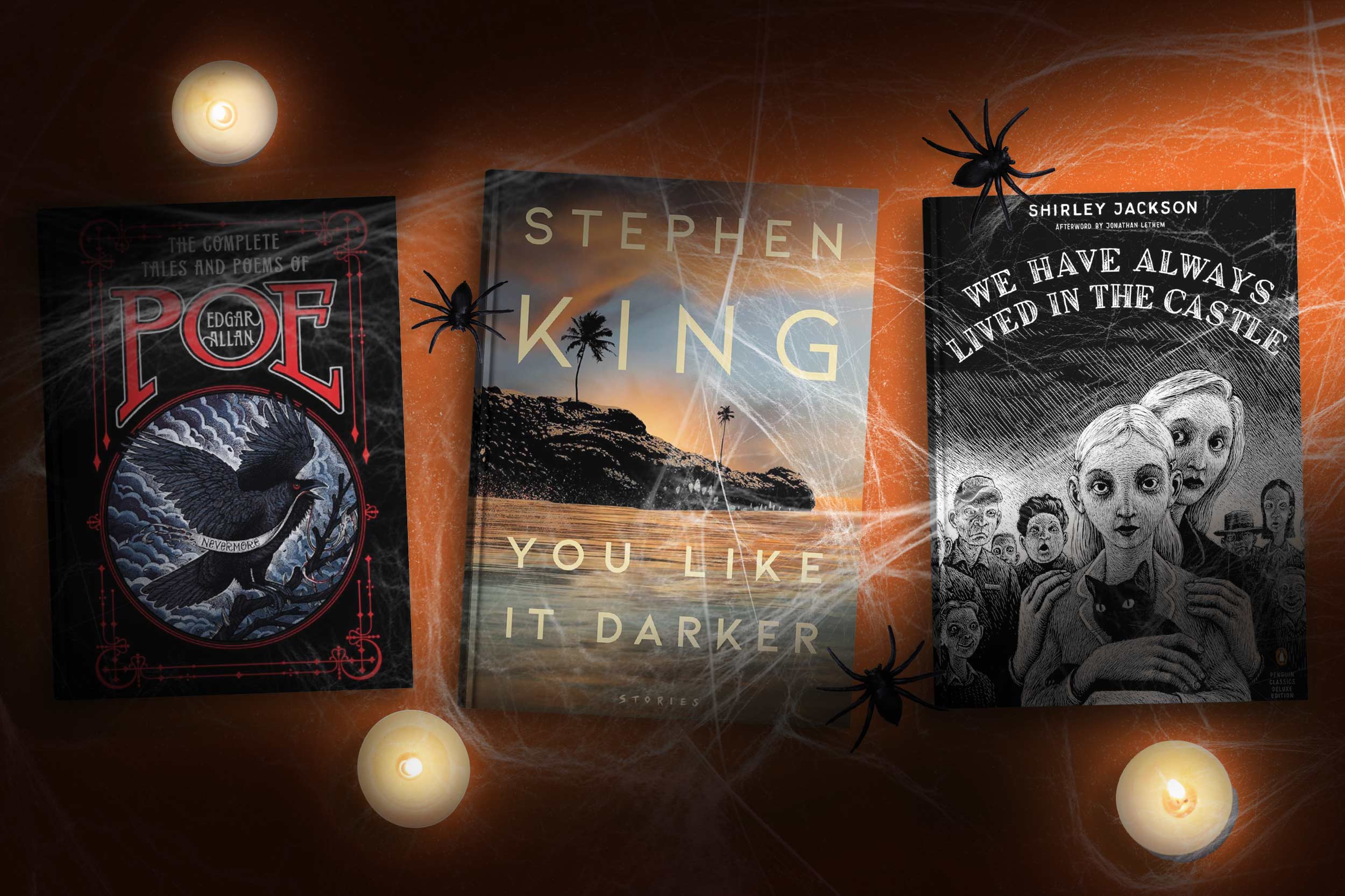 Three books laying on a wooden table: "The Complete Works and Poems of Edgar Allan Poe," which features a drawing of a raven; "You Like it Darker" by Stephen King, which has a picture of an island; and "We Have Always Lived in the Castle" by Shirley Jackson, represented by a white drawing of people's faces on a black background. 