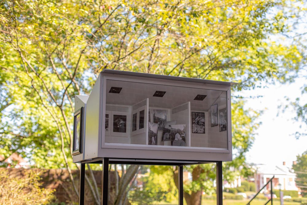 A photo of the Little Museum, a small white box that is divided into tiny rooms. Each room has small black-and-white photos on the "walls," a small diorama of an art gallery.