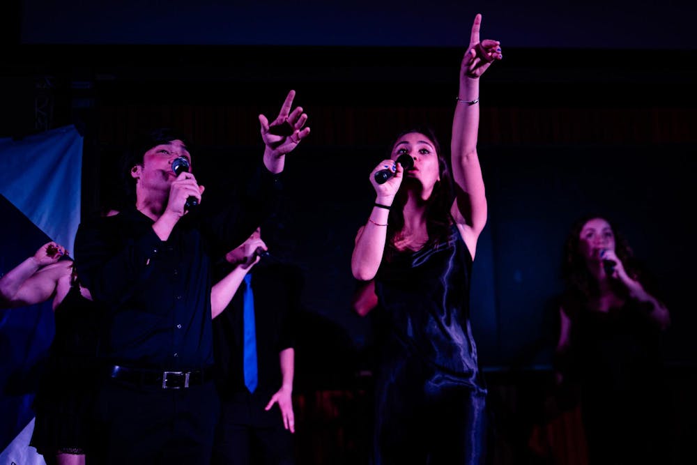 Two singers from The New Dominions acapella group are performing on stage.