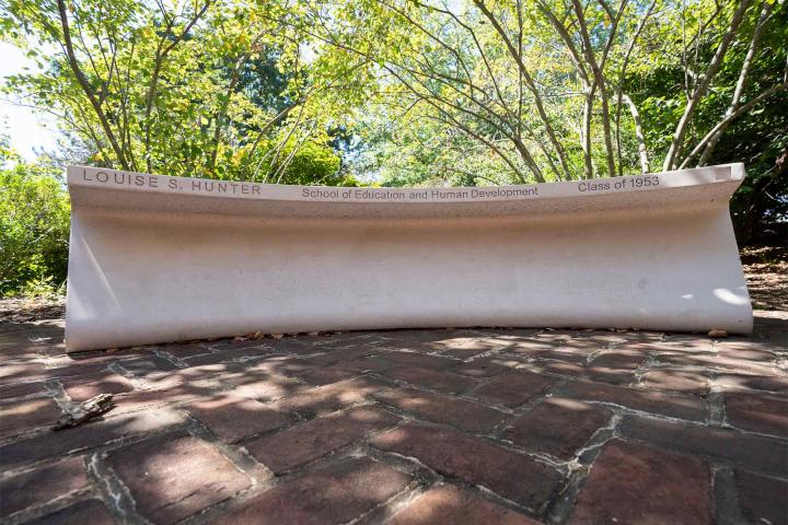 An image of a memorial bench on grounds, remembering Louise Stokes Hunter.