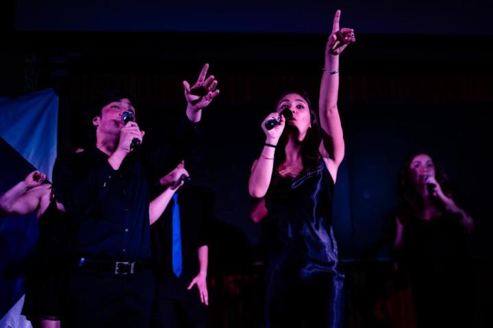Two singers from The New Dominions acapella group are performing on stage.